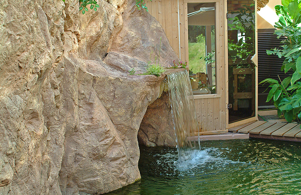 kunstfelsen-privat-saunaanlage-glasfaserbeton Eine private Wohlfühloase mit Sauna, Tauchbecken und einem in die künstliche Felswand integrierten Wasserfall